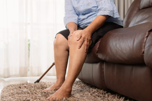senior woman suffering from knee pain at home, health problem co